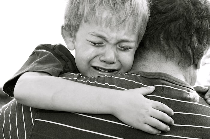 crying child being hugged by father