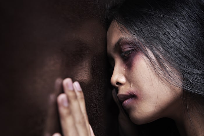 woman with a black eye up against a wall