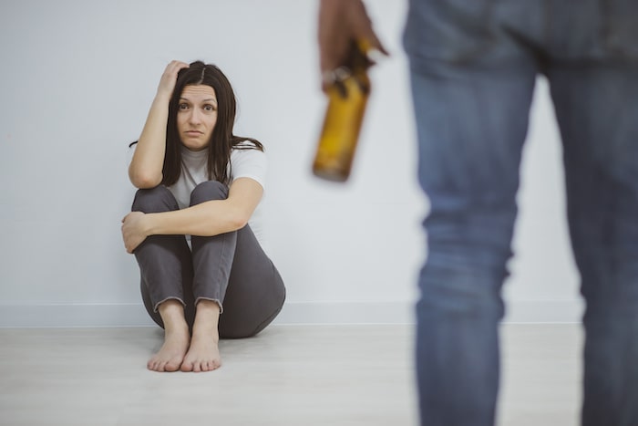 woman looking scared as partner is drinking